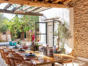 A dining area with a glass table, wicker chairs, and a pergola overhead. - Impressive Farmhouse With Pool (Santa Eulalia del Rio)