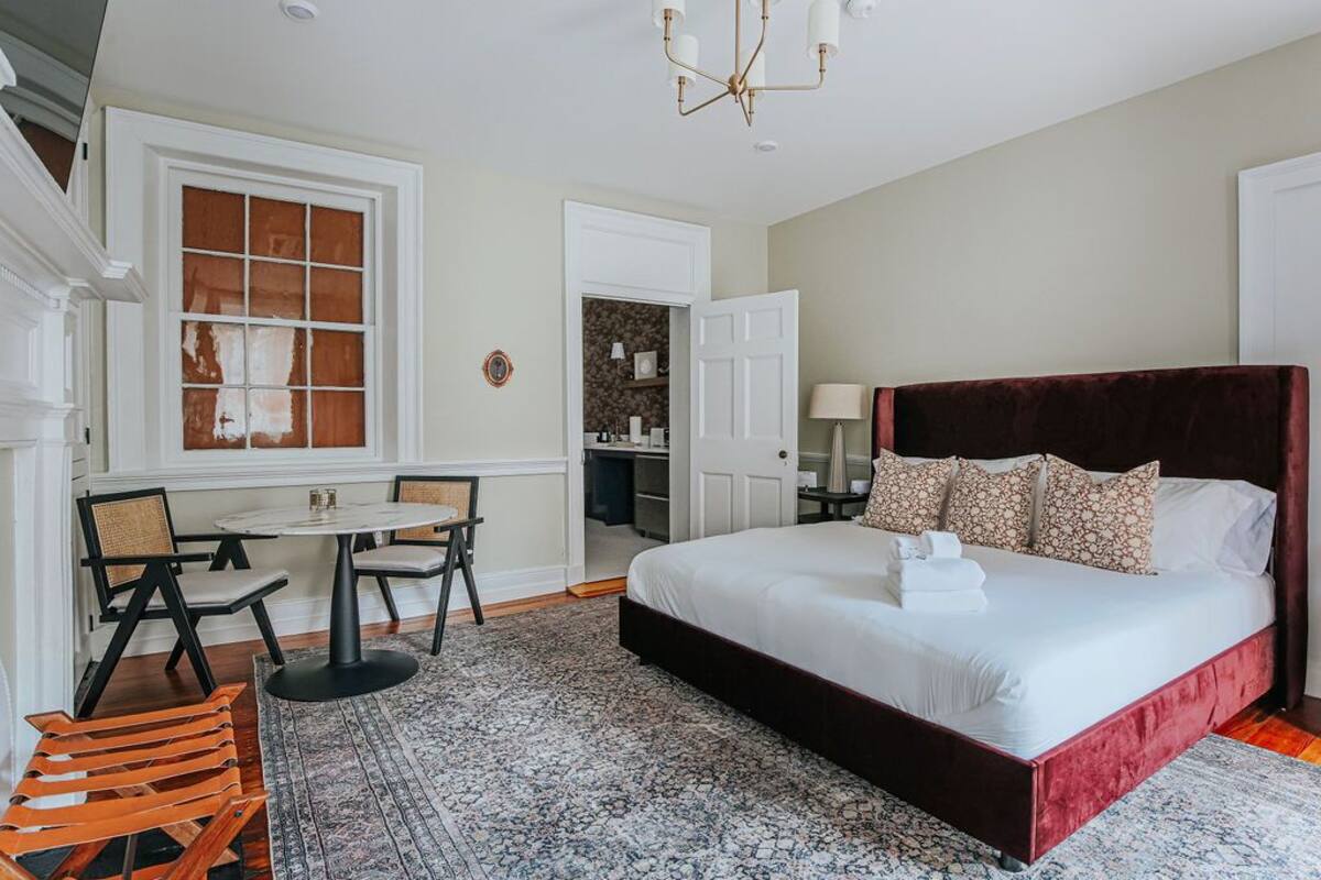 A bedroom with a large bed, a small table, and chairs.