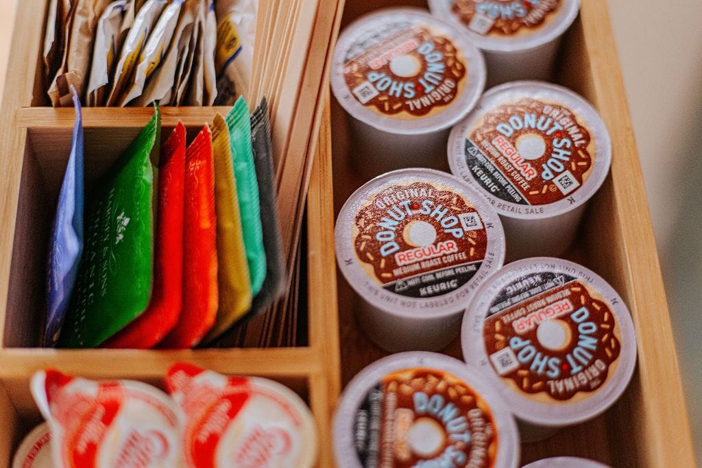 Un plateau en bois contenant divers objets, notamment des enveloppes colorées et des récipients étiquetés « Boutique de beignets ».