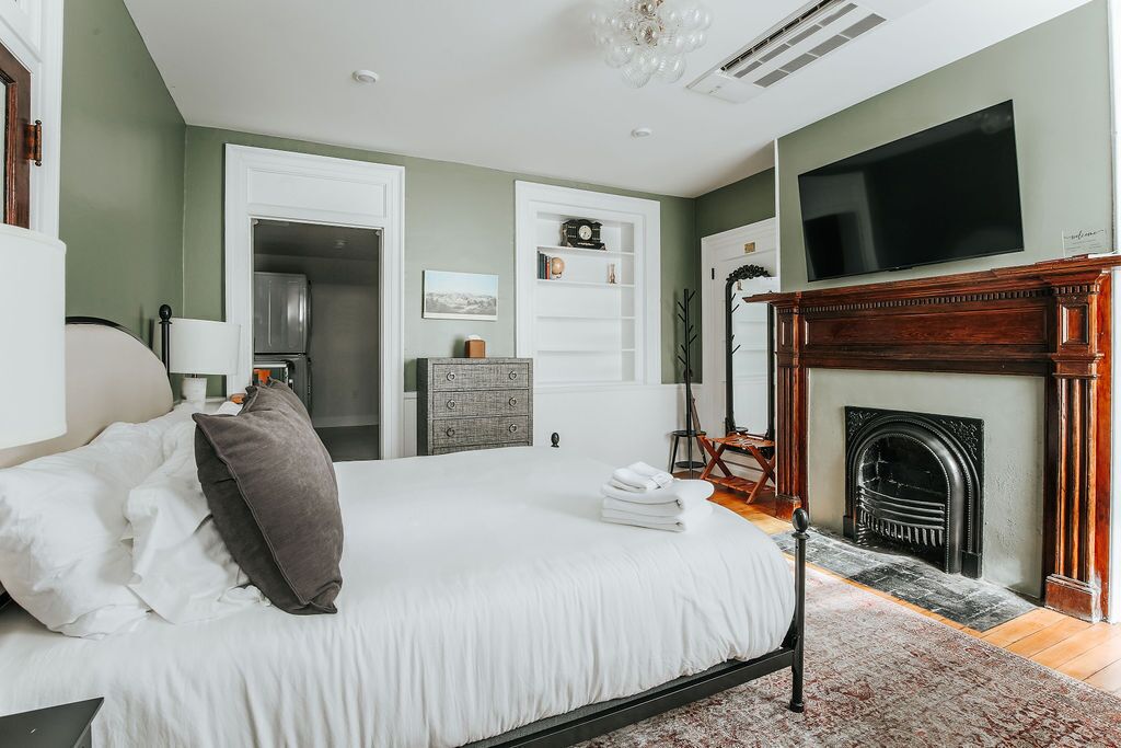 A bedroom with a bed, a television, a fireplace, and a wardrobe.