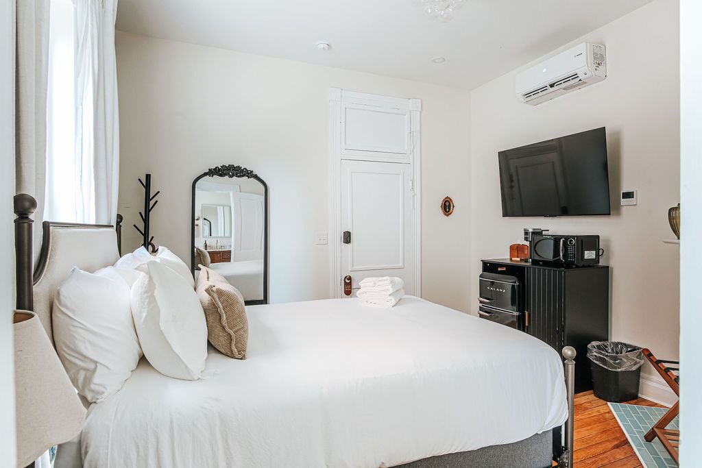 A hotel room with a bed, a flat-screen TV, a microwave, and a minibar.