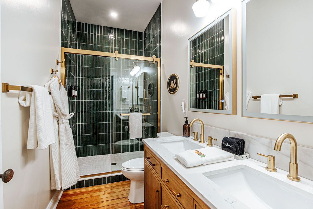 A modern bathroom with a shower, toilet, and vanity with dual sinks and a large mirror.