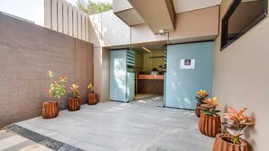 A modern building entrance with a reception desk, potted plants, and a tiled floor. - Abssolute Homtel - Rooms and Suites  (Pune)