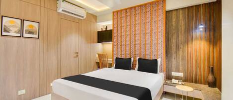 Ein modernes Hotelzimmer mit einem großen Bett, einer Klimaanlage, einem Deckenventilator, einem kleinen Tisch mit Stuhl und einem dekorativen Vorhang.