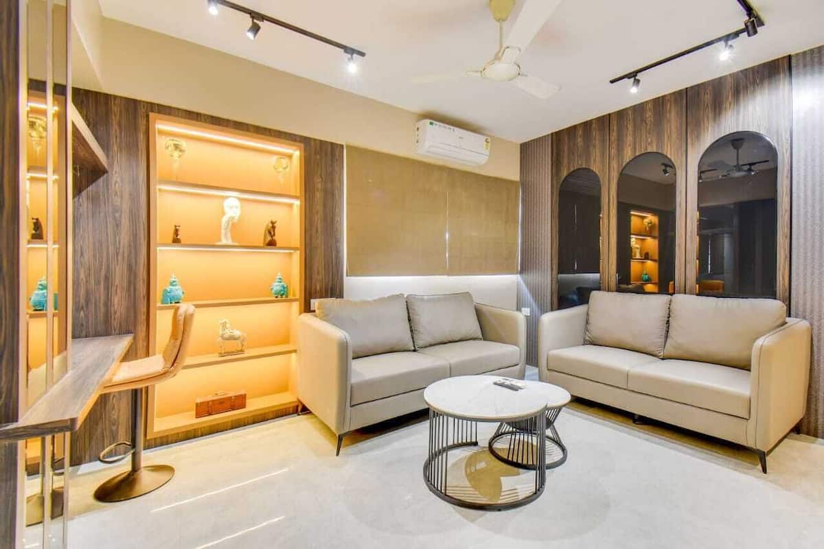 A modern living room with a sofa set, a coffee table, and a decorative shelf with figurines.