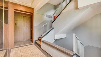 Un interior moderno con una puerta de madera, una escalera con barandillas blancas y un piso con diseño.