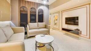 A modern living room with a sofa, a coffee table, and a TV. - Abssolute Homtel - Rooms and Suites  (Pune)