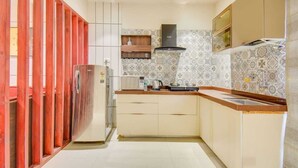A kitchen with a built-in microwave, a stove, and a sink. There is a wooden cabinet and a countertop. - Abssolute Homtel - Rooms and Suites  (Pune)