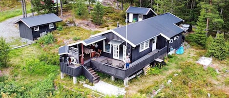Une cabane avec une terrasse, un porche et un garage.