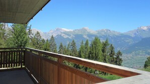 A wooden balcony with a concrete roof overlooking a mountainous landscape. - Luxury Apartment With View (Veysonnaz)
