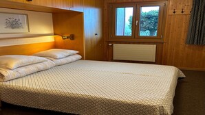 Une chambre à coucher avec un lit, des murs en bois, une fenêtre et un radiateur.
