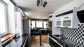 A modern kitchen with black and white checkered backsplash, stainless steel appliances, and a black countertop. - Holiday Apartment in Nature (Frenstat pod Radhostem)