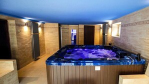 A spa room with a hot tub, wooden paneling, and a bench. - Holiday Apartment in Nature (Frenstat pod Radhostem)