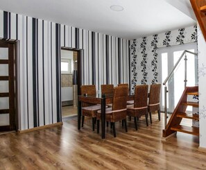 A dining area with striped wallpaper, a wooden staircase, and a view into another room. - Holiday Apartment in Nature (Frenstat pod Radhostem)