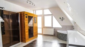 A modern bathroom with a glass shower enclosure, a wooden sauna, and a white bathtub with mosaic tiles. - Holiday Apartment in Nature (Frenstat pod Radhostem)