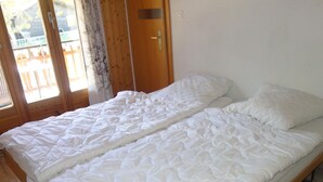 A single bed with a white duvet in a room with wooden flooring and a wooden door. - Apartment With Breathtaking Hill View (Veysonnaz)