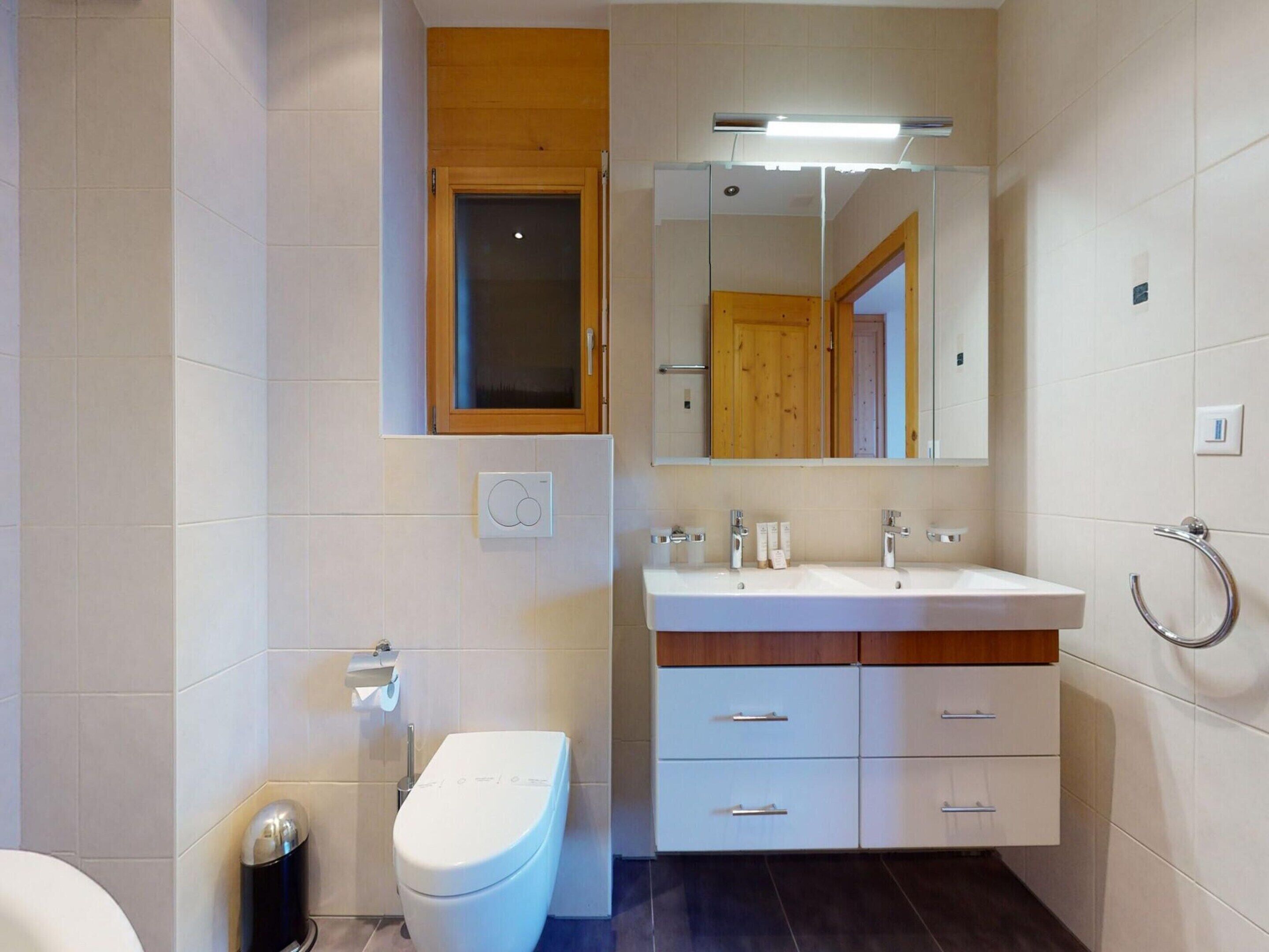 A modern bathroom with a toilet, sink, and vanity.