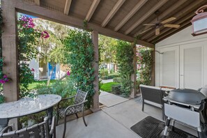 Eine Terrasse im Freien mit Grill, Sitzgelegenheiten und Blick auf einen Garten.