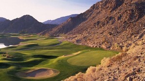 Un parcours de golf avec un lac, entouré de montagnes.
