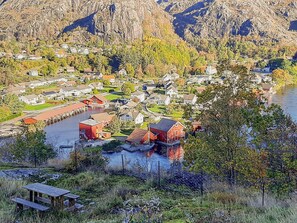 A coastal village with houses along the waterfront, a dock, and a picnic table in a grassy area. - 6 Person Holiday Home in Ana-sira (Sokndal)