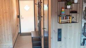 Ein Holzbodenkorridor mit einer Bank, einer Tür mit einem Zettel und einem Regal mit Büchern und Pflanzen.