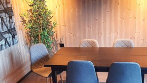 Ein Konferenzraum mit einem Holztisch und vier Stühlen, einer davon mit einer gesteppten Rückenlehne.