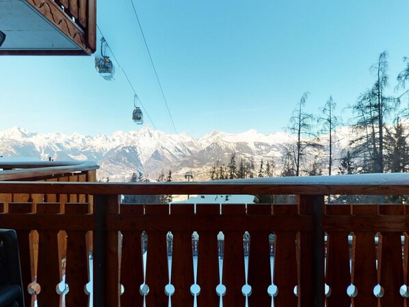 A wooden deck with a view of snow-covered mountains and a ski lift in the background. - Apartment Surrounded With Nature (Veysonnaz)