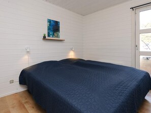 A bedroom with a bed, a wall-mounted shelf with a plant, and a painting. - 4 Star Holiday Home in Vaeggerlose (Vaeggerlose)