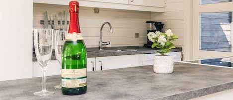 Una cocina con una encimera, una botella de vino y un florero con flores.