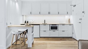 A modern kitchen with white cabinetry, a wooden countertop, and a built-in oven. - Studio4: Bondi Chic Interiors with Rooftop Pool (Bondi Junction)