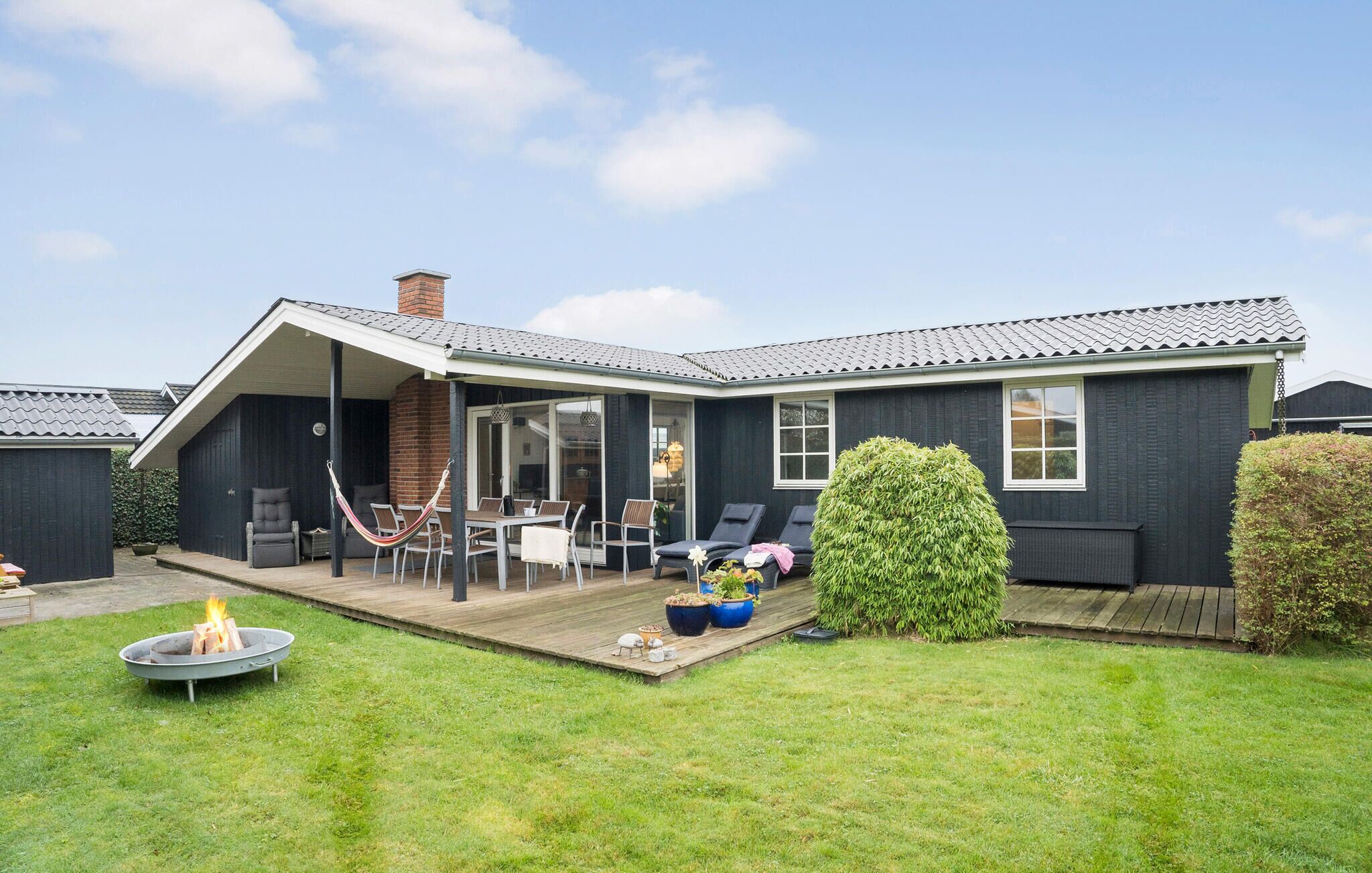 A house with a covered patio, a fire pit, and a neatly trimmed lawn.