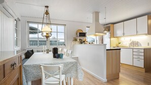 Una cucina moderna con mobili bianchi, un tavolo da pranzo con sedie e una lampada a sospensione.