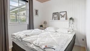 Una camera da letto con un letto, una finestra con tende, un comodino con una lampada e decorazioni a parete.