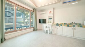 A modern kitchen with white cabinets, a tiled backsplash, and a built-in TV. - Gangreung Comichi Bada Pension (Gangneung)