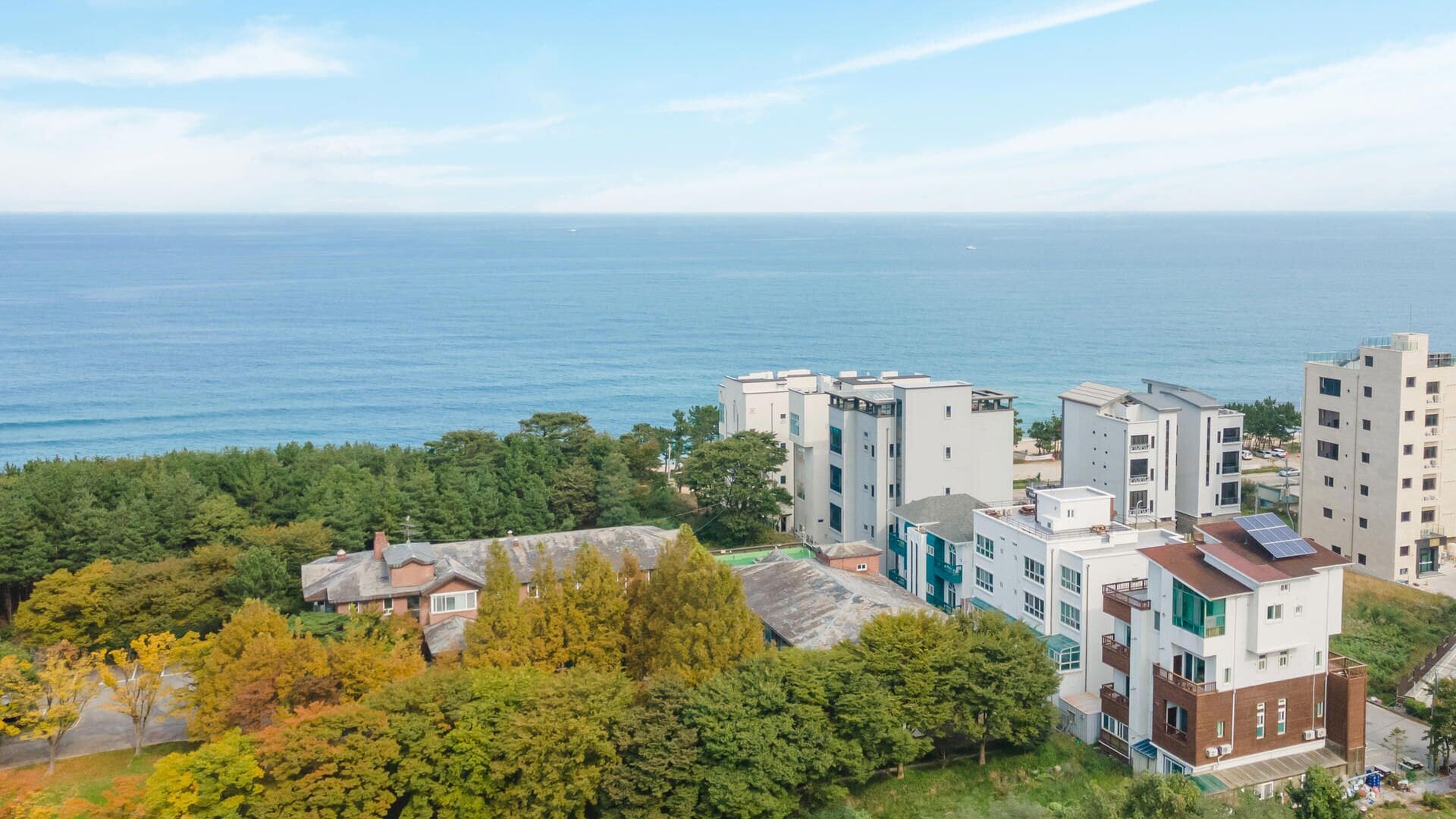 Ein Küstenwohngebiet mit modernen Gebäuden, Blick aufs Meer und umliegender Bepflanzung.