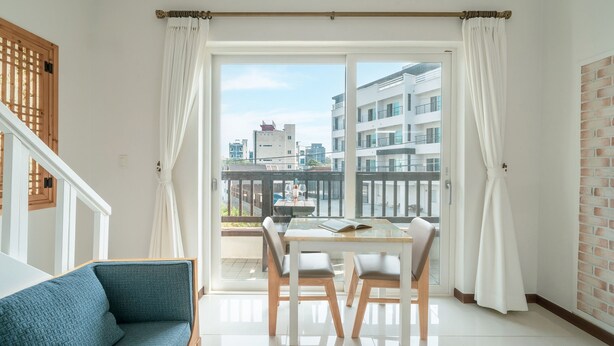 A modern apartment with a balcony, a dining area, and a view of the cityscape. - Gangreung Comichi Bada Pension (Gangneung)