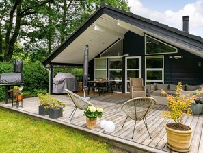 A modern outdoor deck with a dining area, seating, and a barbecue setup.