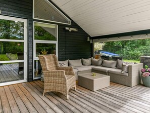 A covered outdoor seating area with wicker furniture and a view of the garden.