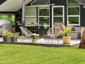 A patio with outdoor furniture, a covered grill, and potted plants.