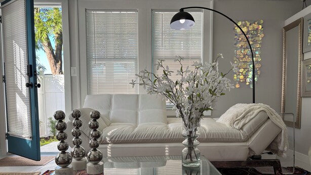 A modern living room with a glass coffee table, white sofa, and a colorful rug.