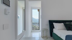 Una habitació d'hotel moderna amb un llit, una taula de nit, vista a les muntanyes a través de la porta del balcó i un disseny net i minimalista.