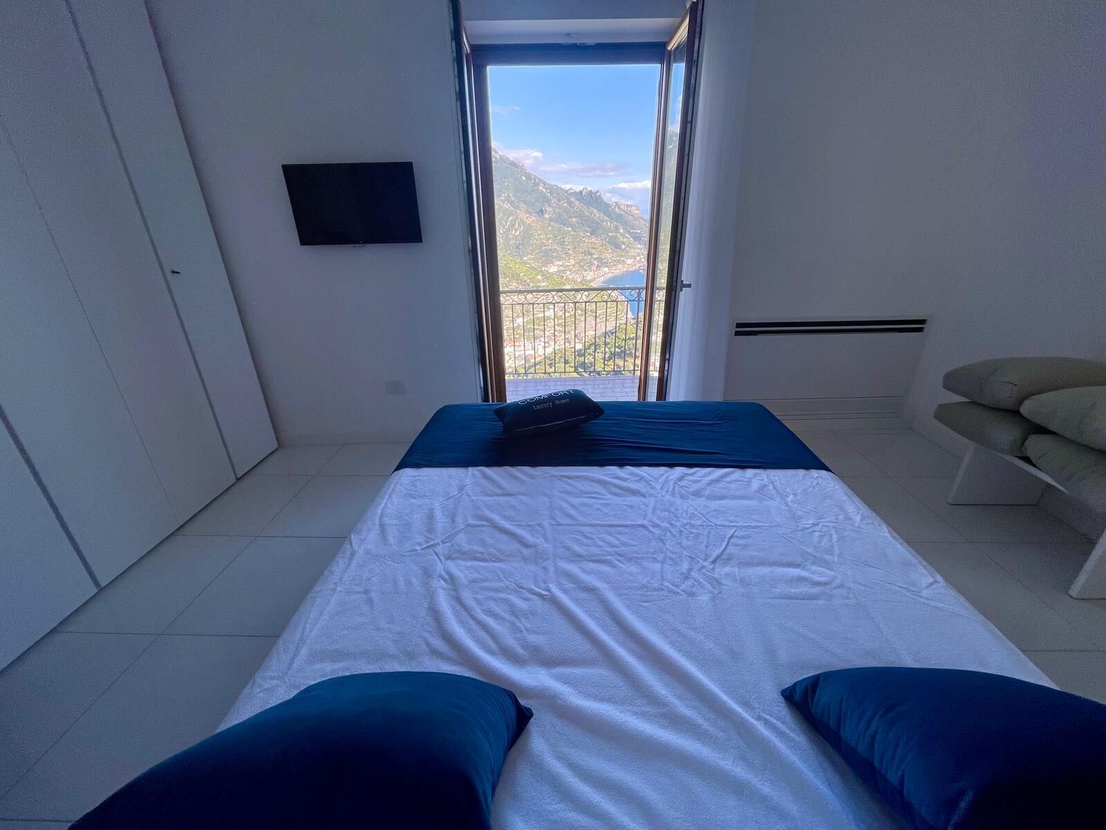 Une chambre avec un lit, une télévision et un balcon offrant une vue sur la montagne.