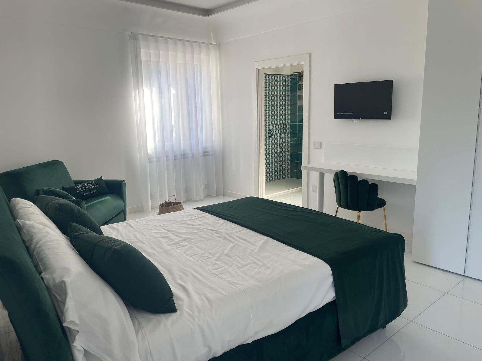 A modern bedroom with a bed, a TV, and a view of a balcony.