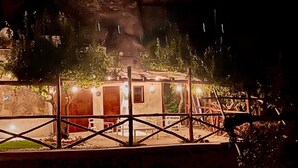 Una construcció rústica de tipus cabana, amb teulada i parets de fusta, envoltada per una tanca metàl·lica.