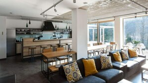 A modern kitchen with a central island, bar stools, and a dining area with a sofa and chairs. - Comfortable Villa With Pool (Mala Moravka)