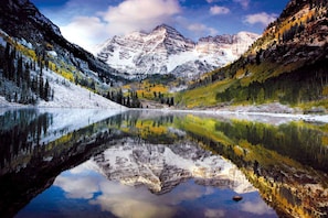 A mountain lake with reflections of the surrounding mountains and trees. - Woodbridge 21E (Snowmass Village)