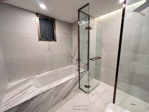 A modern bathroom with a glass-enclosed shower, a large bathtub, and marble walls. - The Peak Midtown - Gorgeous Riverside (Ho Chi Minh City)