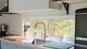 A modern kitchen with a window, stainless steel sink, and light blue cabinets. - 4 Person Holiday Home in Askloster (Åskloster)