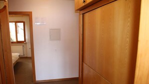 A room with a wooden wardrobe, a bed, a radiator, and a window with curtains. - Stunning Apartment With Mountain Views (Veysonnaz)