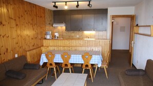 A cozy room with a wooden wall, a dining table with chairs, a sofa, and a small table. - Stunning Apartment With Mountain Views (Veysonnaz)